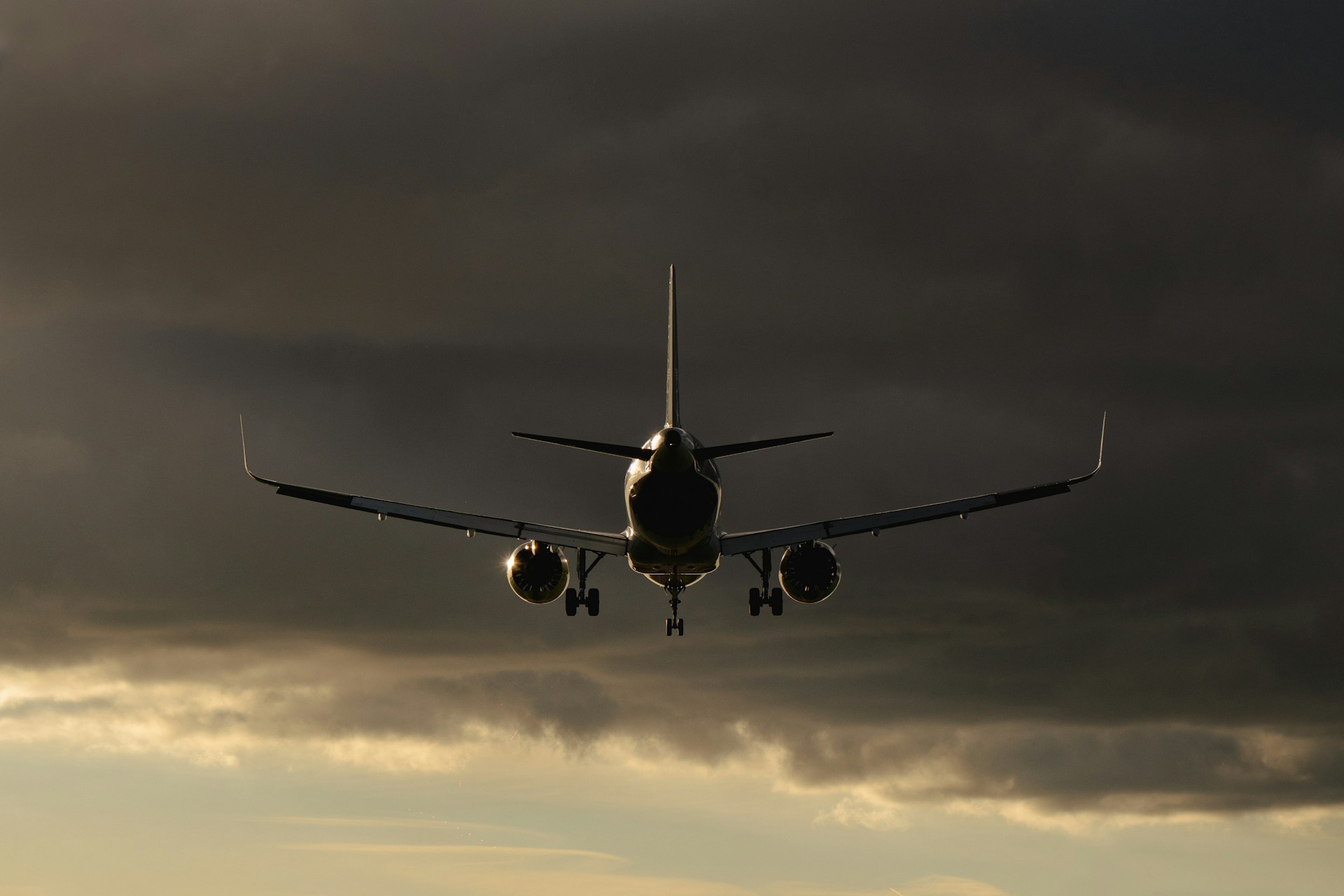 Et stort jetfly flyr mot en skyfull, mørk himmel